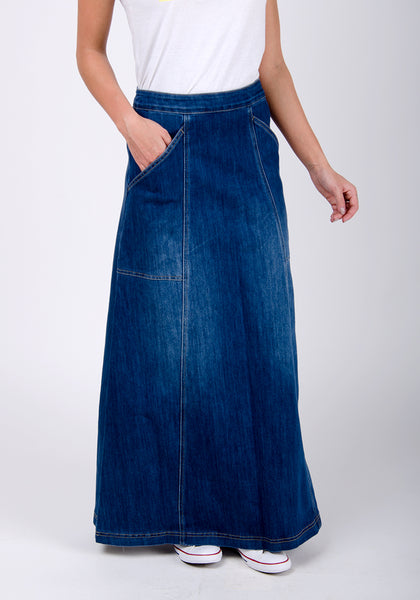 Ankle-length maxi-denim skirt with hand in right pocket.