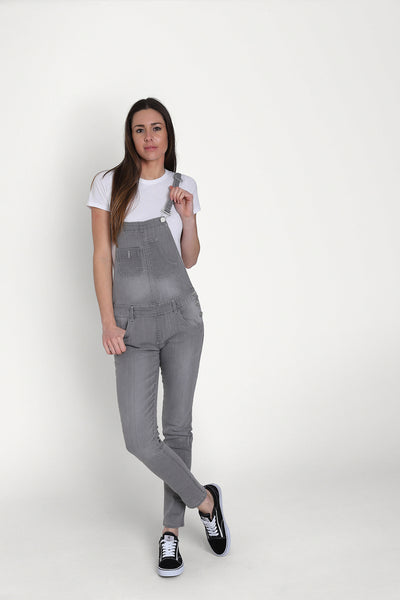 Grey ‘Talia’ style skinny fit dungarees for women, paired with white t-shirt and dark trainers.