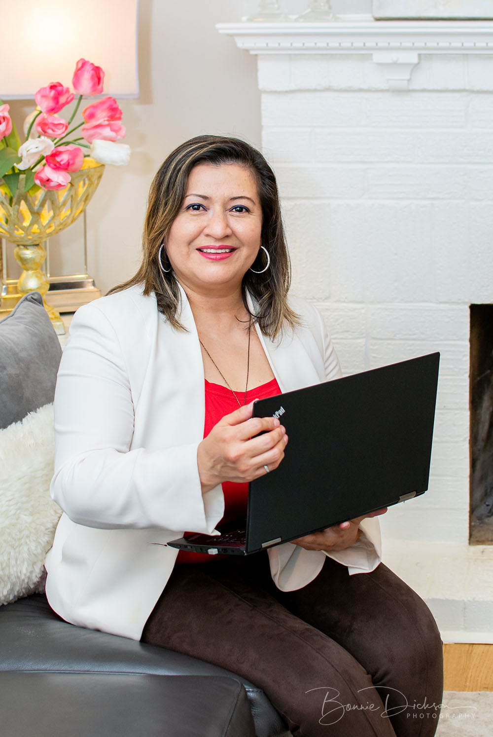 Woman sitting holding a laptop and smiling