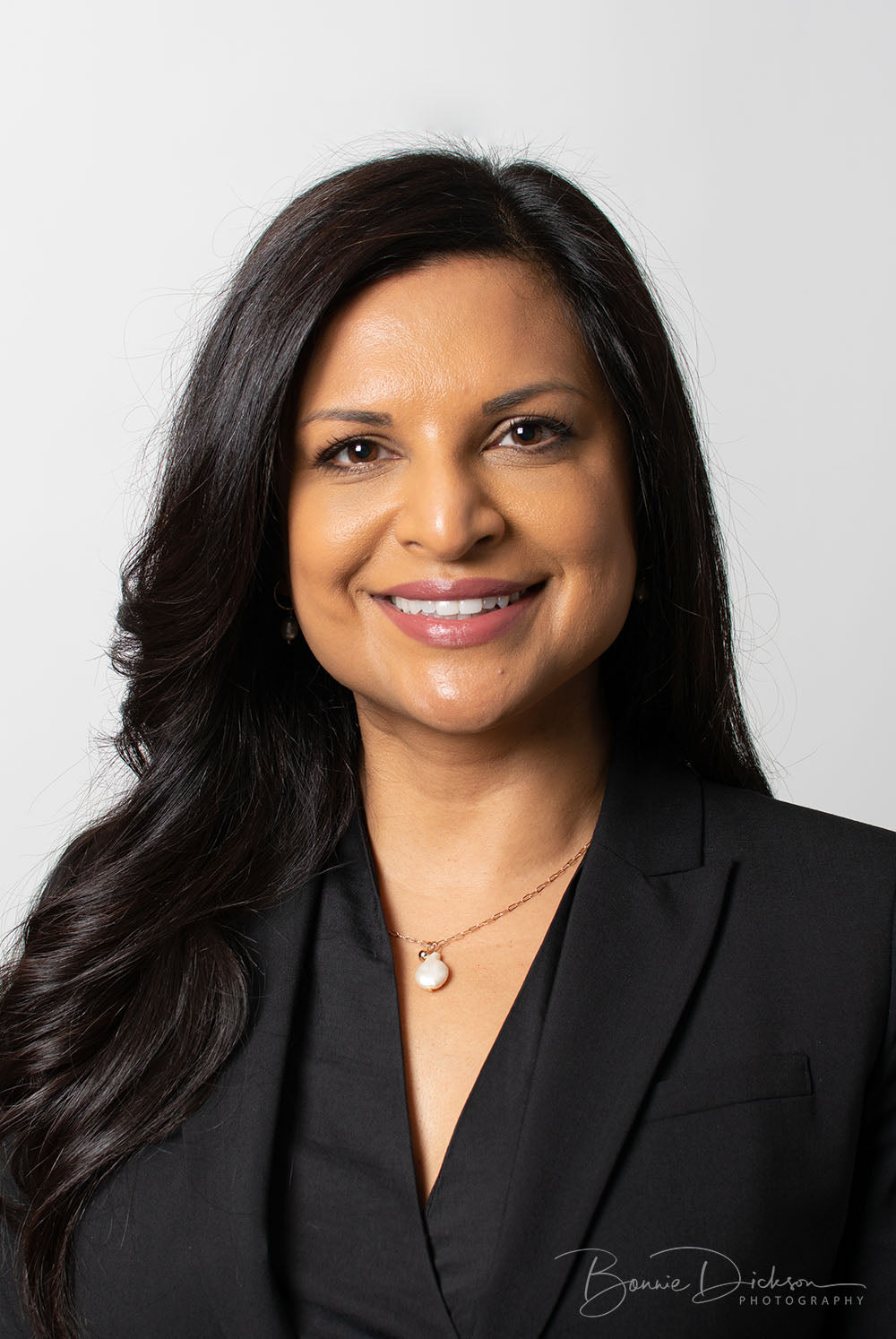 Woman with black hair and black suit jacket smiling