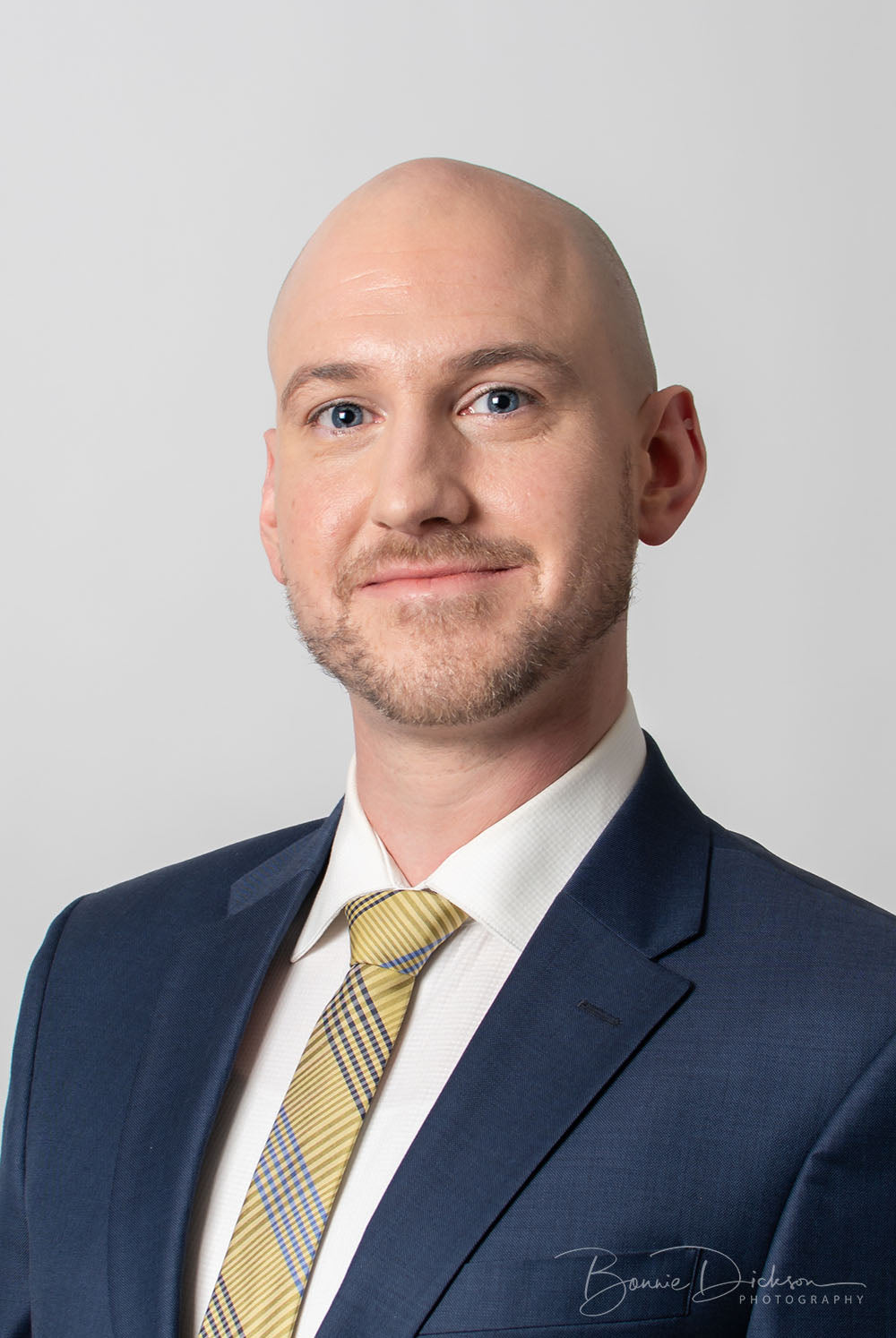 Bald man with blue suit jacket smiling