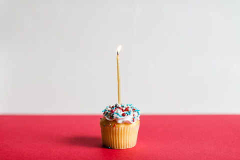 cupcake with sprinkles on it and a lit candle in the middle