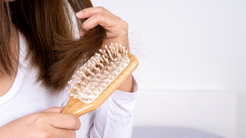 brunette woman whose hair loss is visible on her brush, full of hair