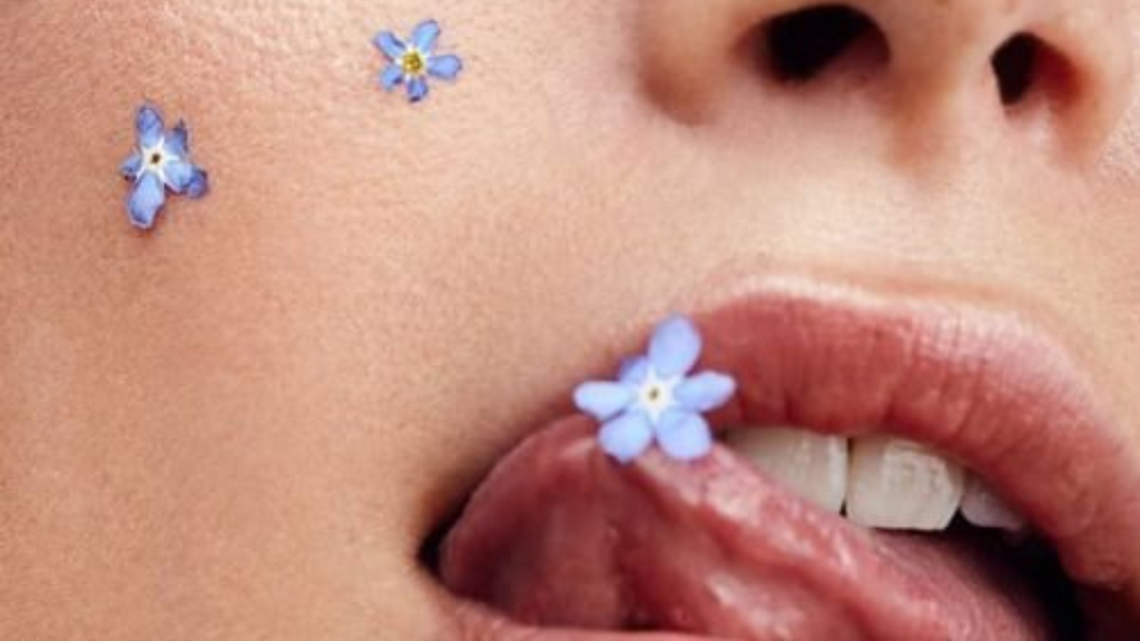 bouche entrouverte avec la langue tentant d'attraper une fleur sur la lèvre supérieure évoquant subtilement la phytothérapie et ses bienfaits