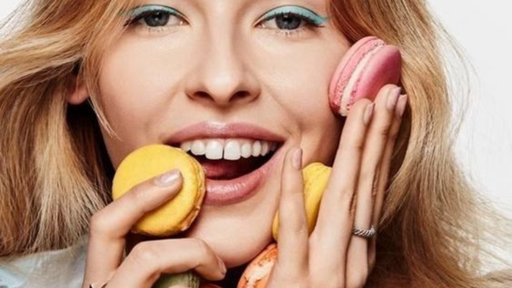 blonde woman holding yellow and pink macaroons