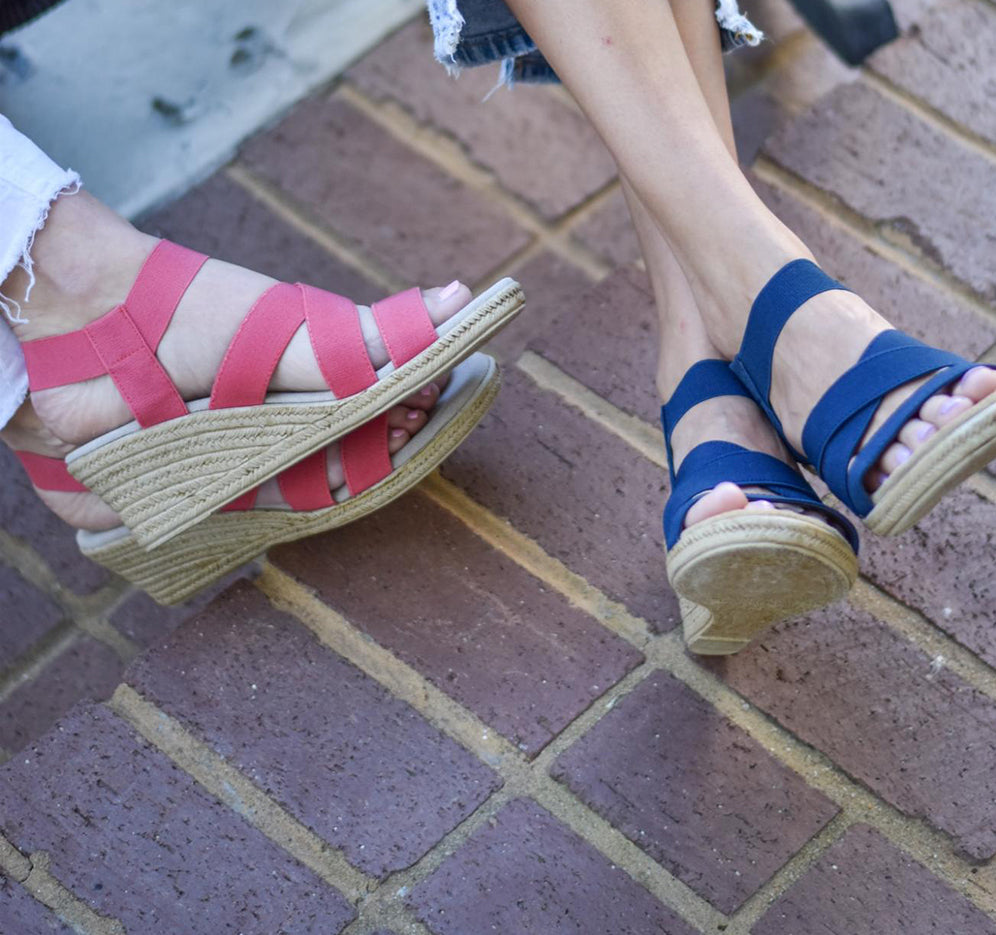 a couple of women wearing x strap sandals in pink and blue
