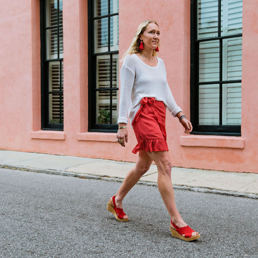 a woman walking down the street wearing med ankle strap wedges in red
