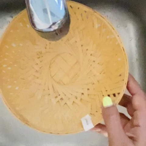 Washing bamboo basket under tap water