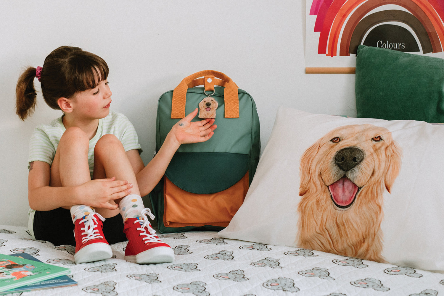 girl in styled kids room holding golden retriever dog key chain on her green school bag 