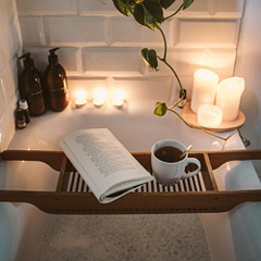 Image of a bathtub of water with candles and a book.