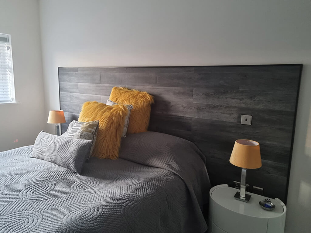 A bed headboard created with our grey vinyl peel and stick panels