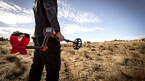 man holding a minelab vanquish metal detector in a field