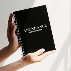 Hands holding an Abundance budgeting journal on white background