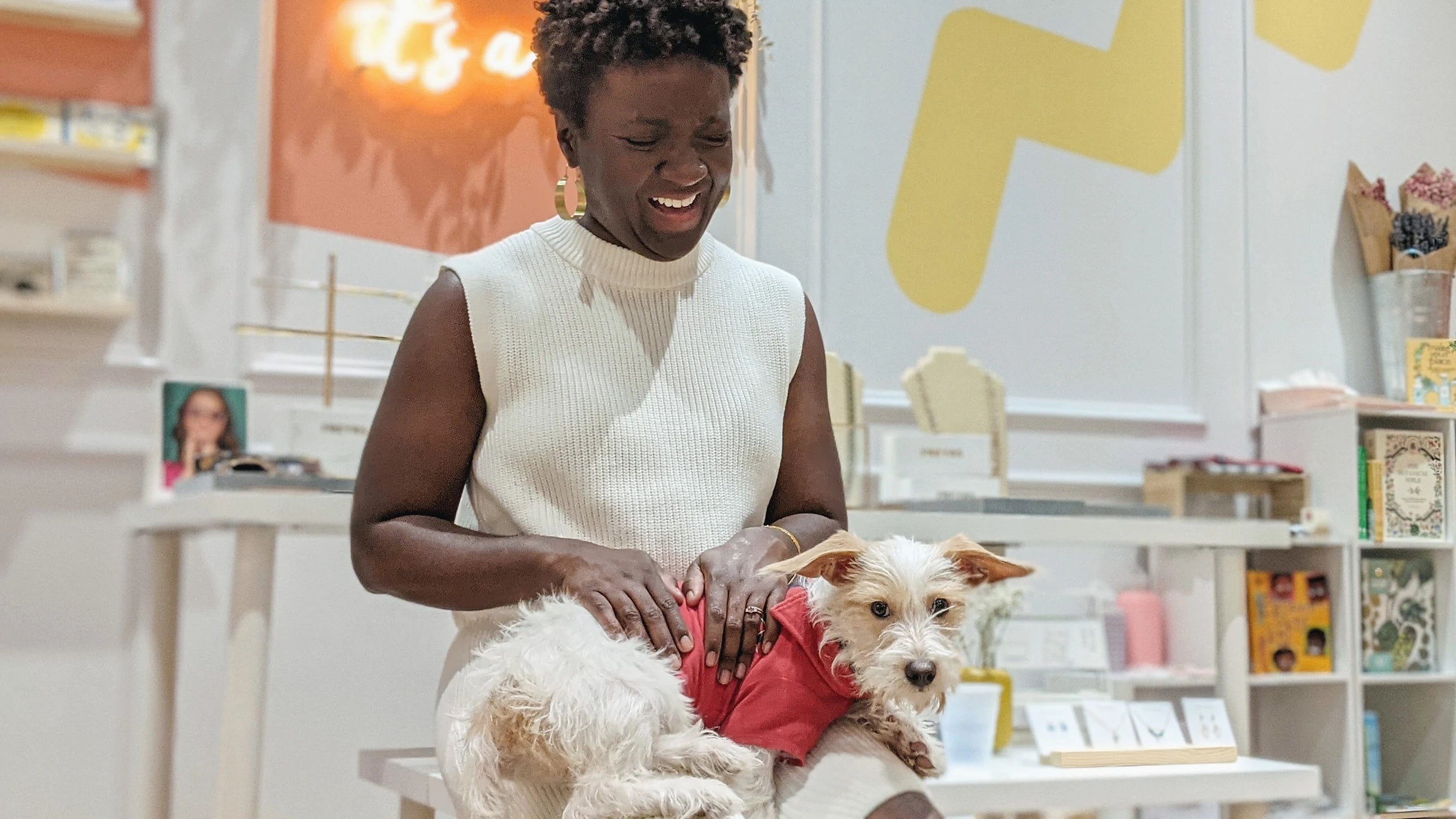 Black woman laughing with a dog on her lap