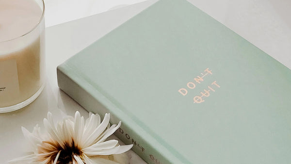 A cyan journal with gold letters that says "don't quit"