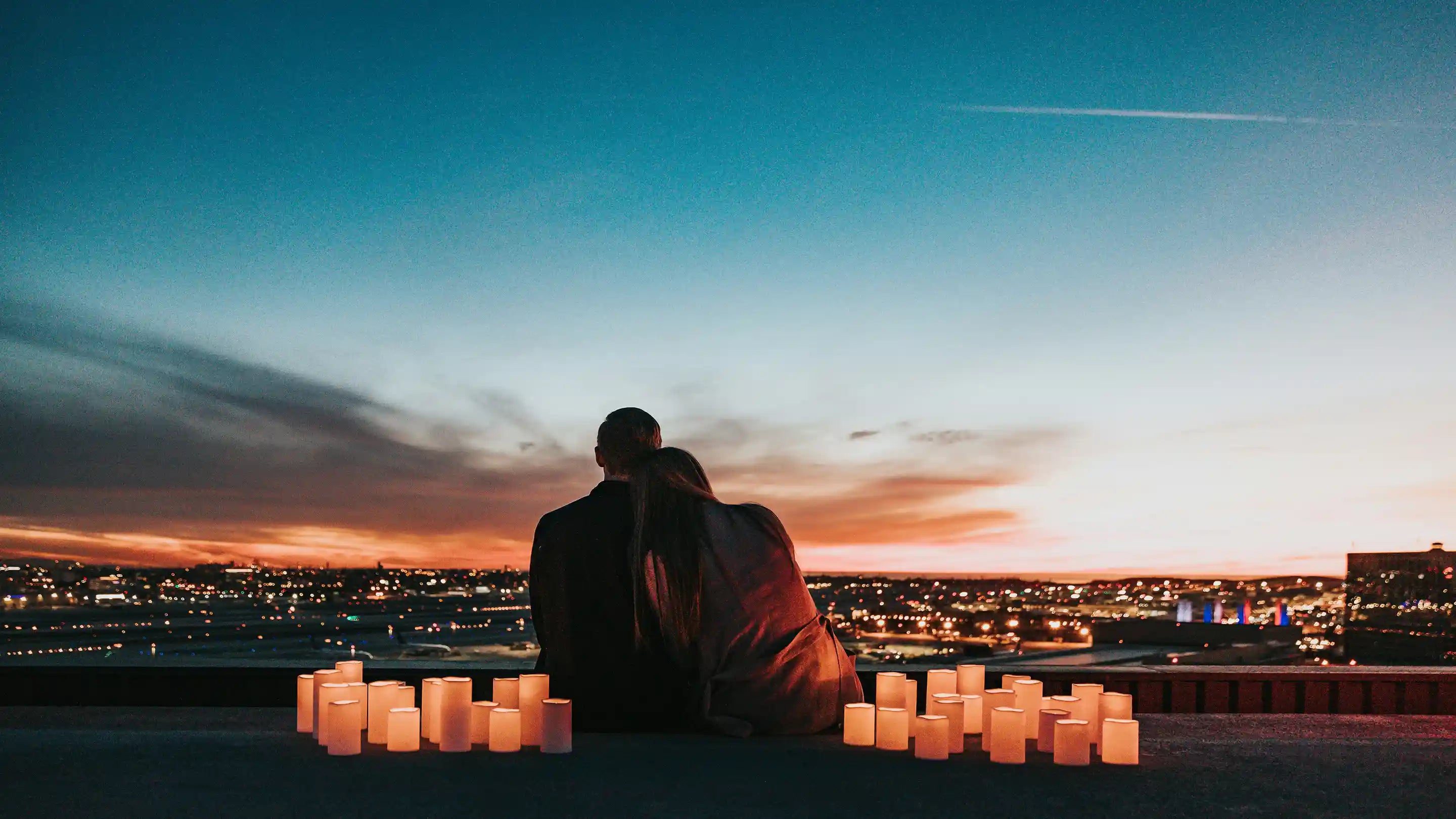 A couple sitting by candles looking into the sunset
