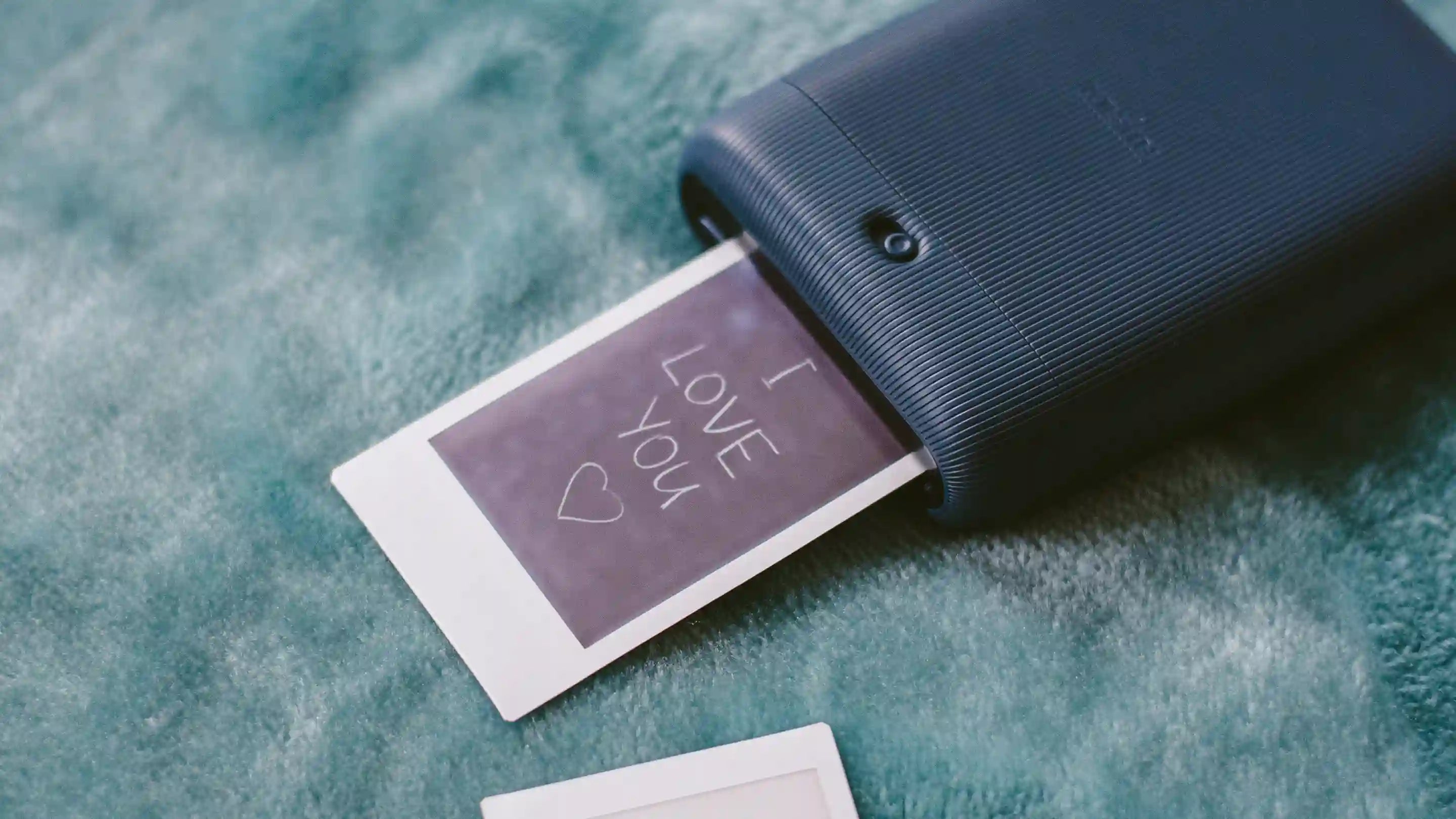 A portable polaroid printer printing out a message that says I Love You