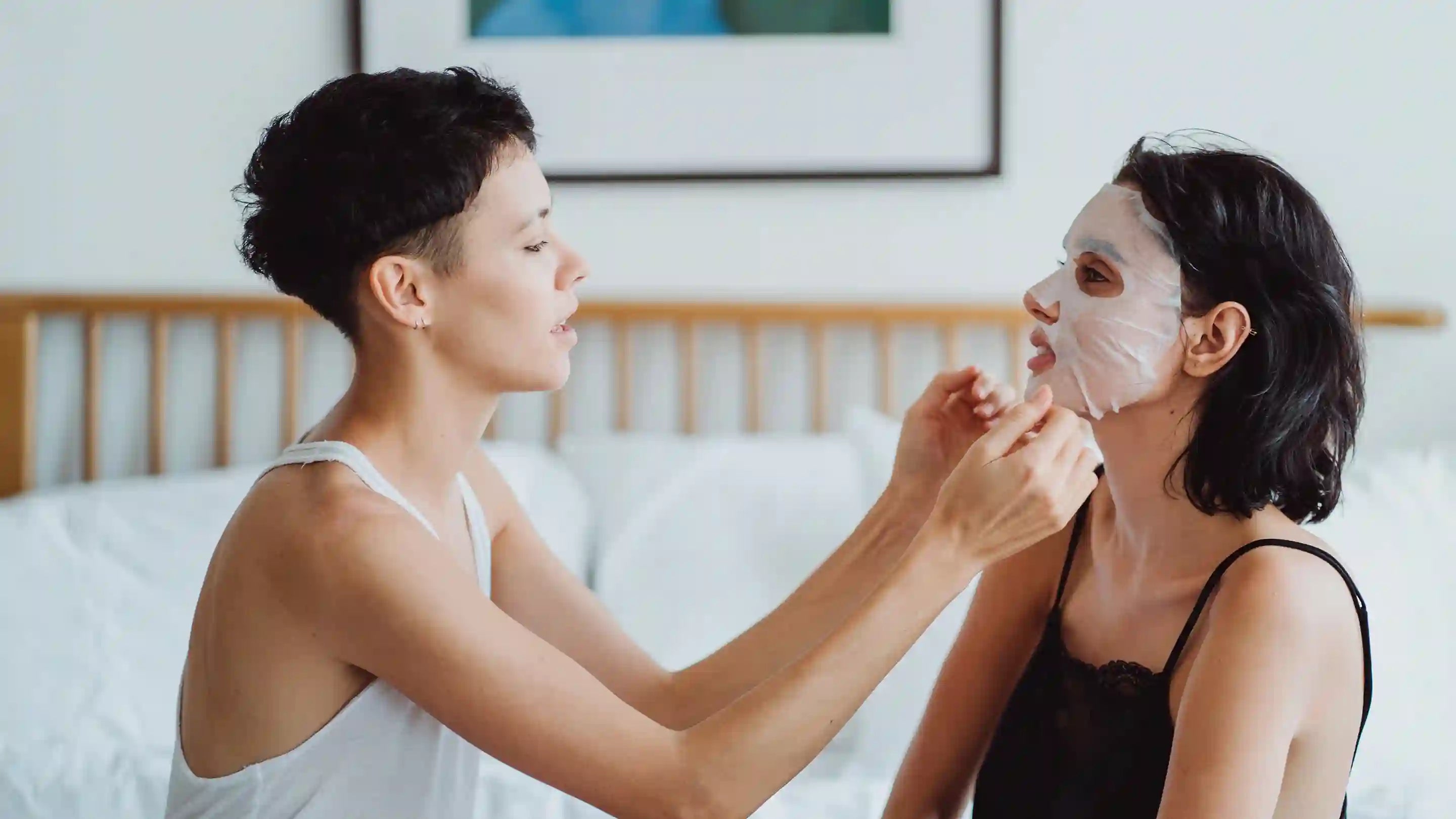 A woman placing a facial mask on another woman