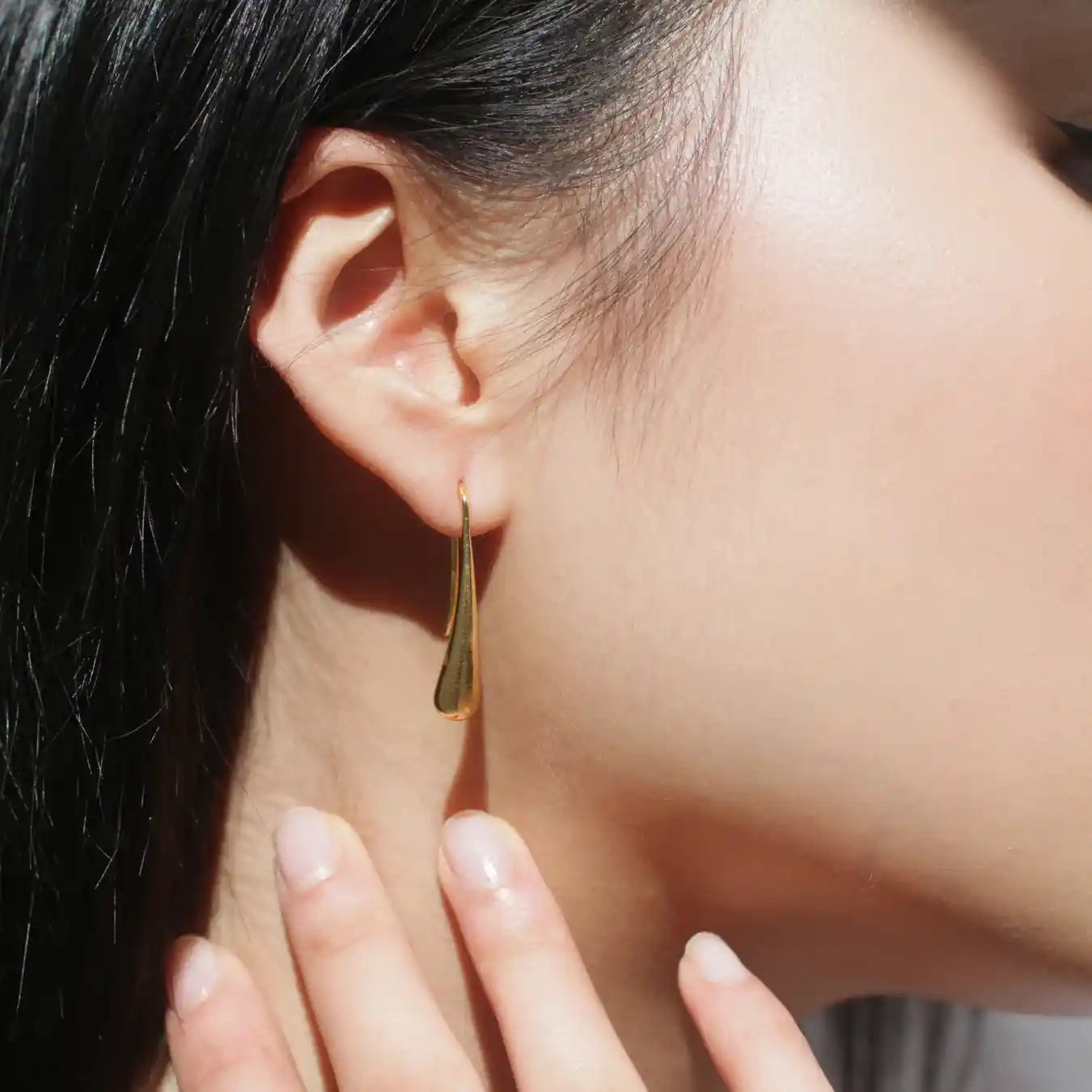 A woman's profile. She is wearing gold earrings 