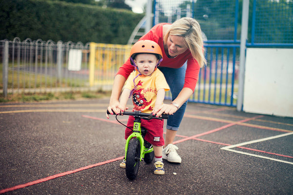 child on green balance bike