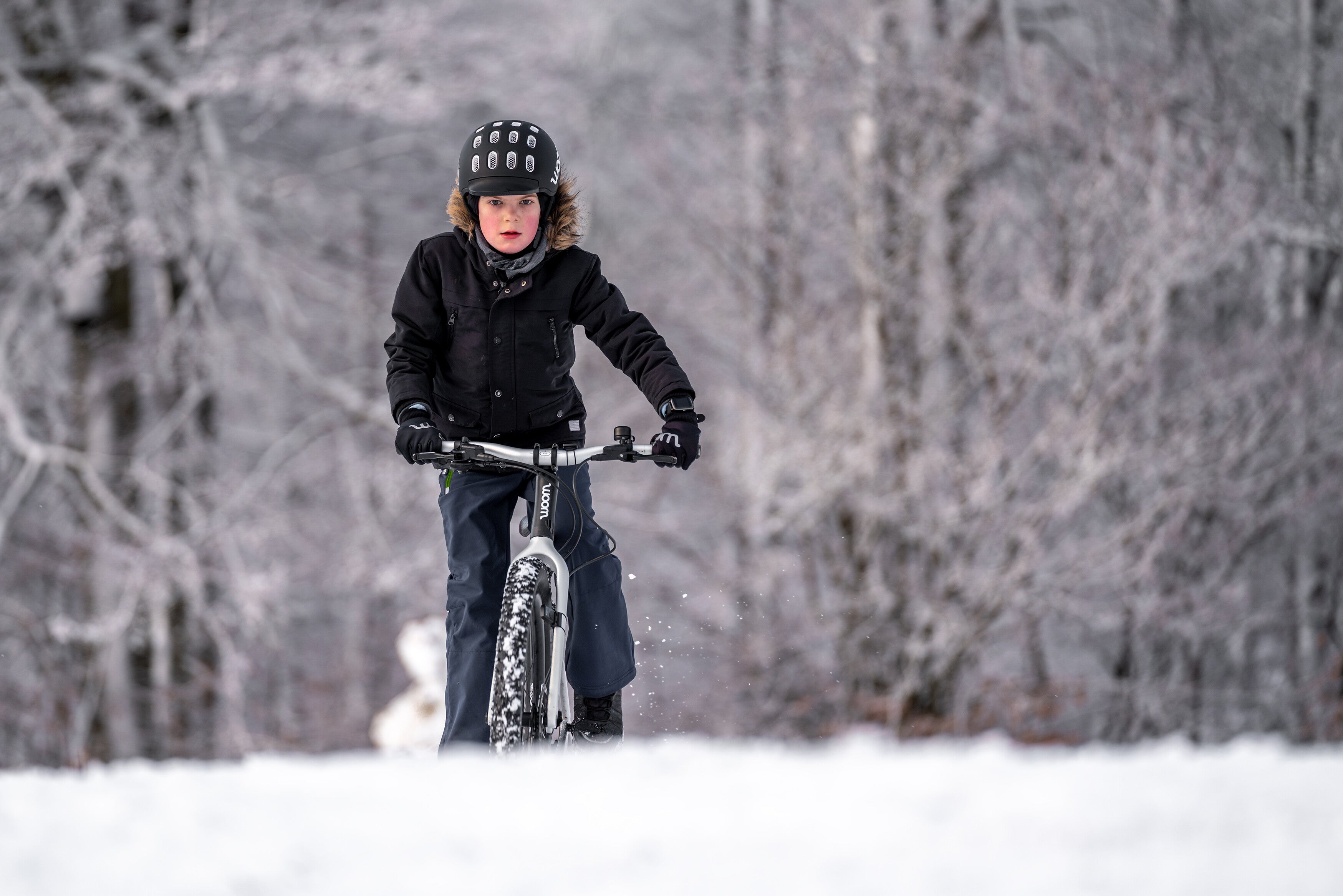 boy in snow with a woom bike