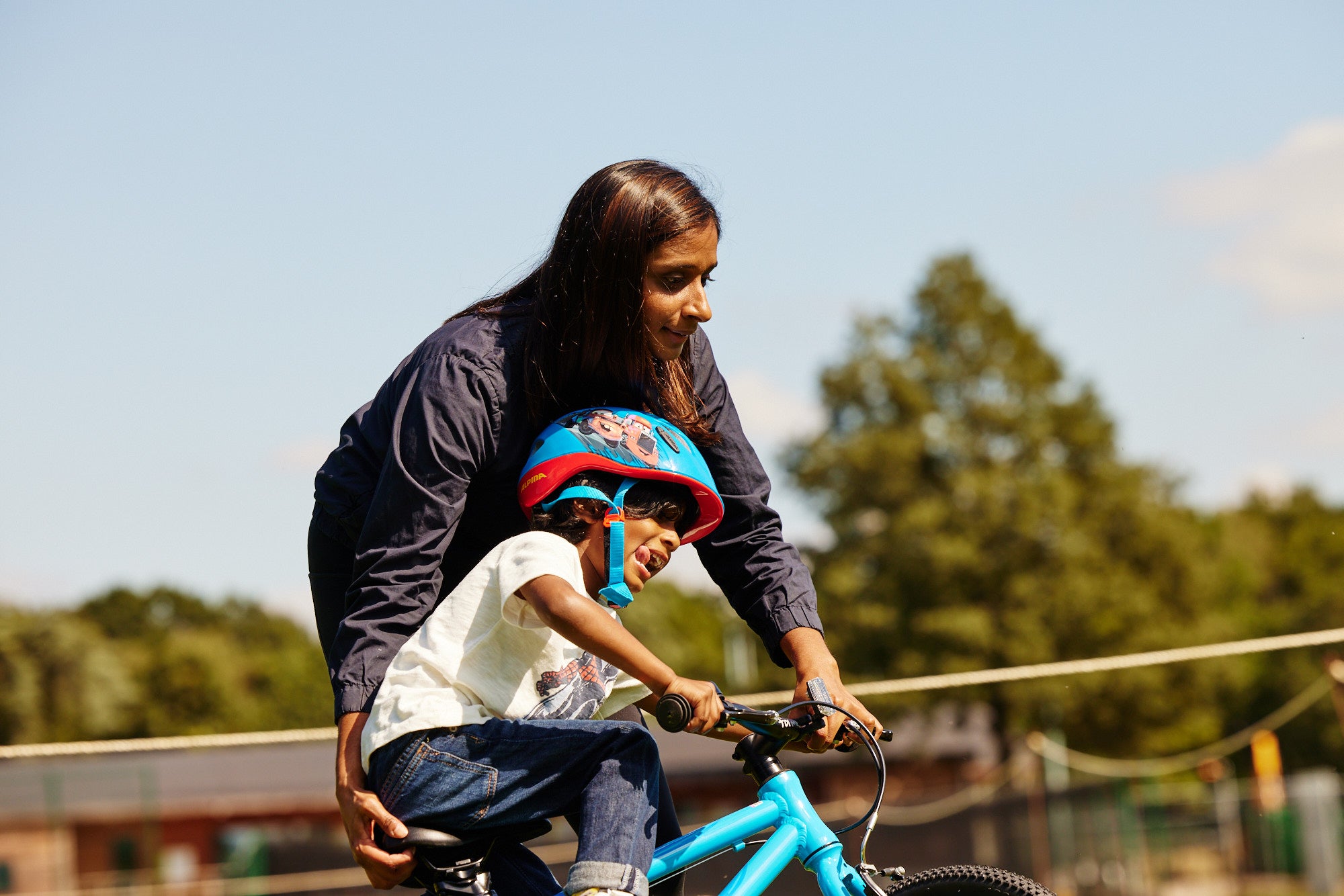 parent helping their child to ride a bike