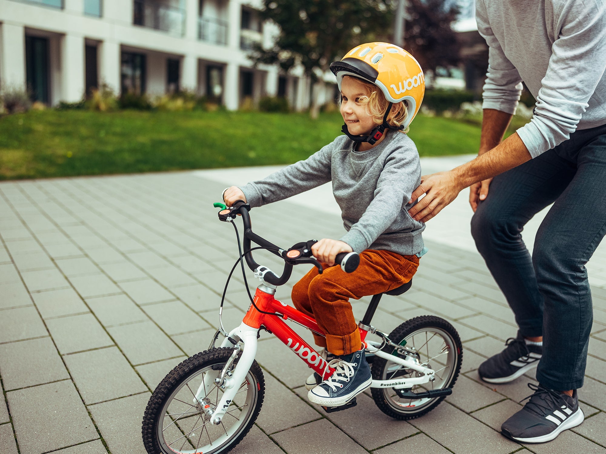 child riding a woom 2 in the street