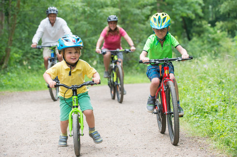 A family cycling in the woods wearing well-fitted helmets