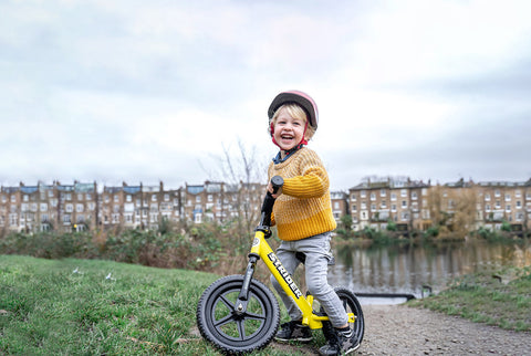 A child on a Strider balance bike in the outdoors