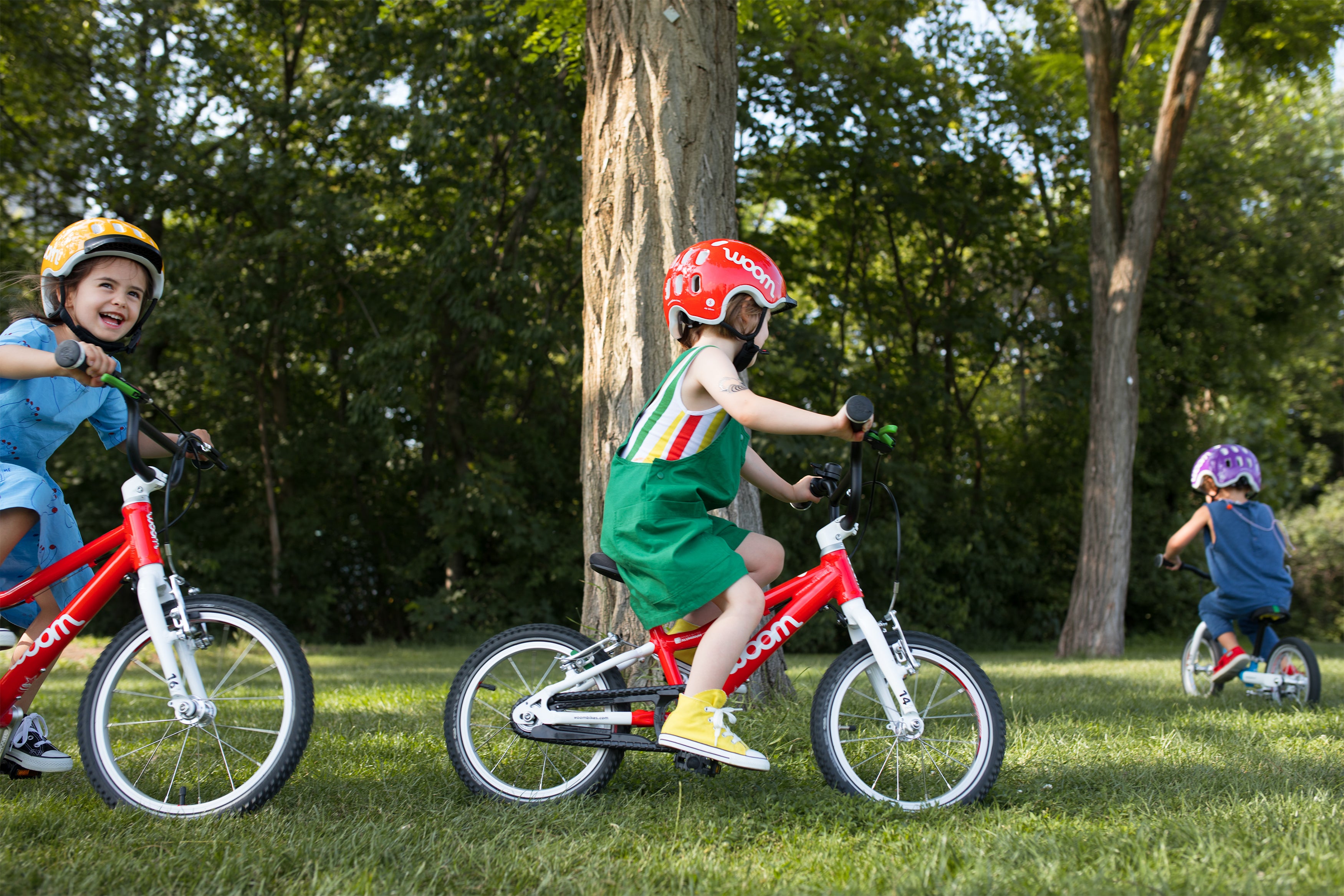 three kids riding their Woom first pedal bikes in the outdoors