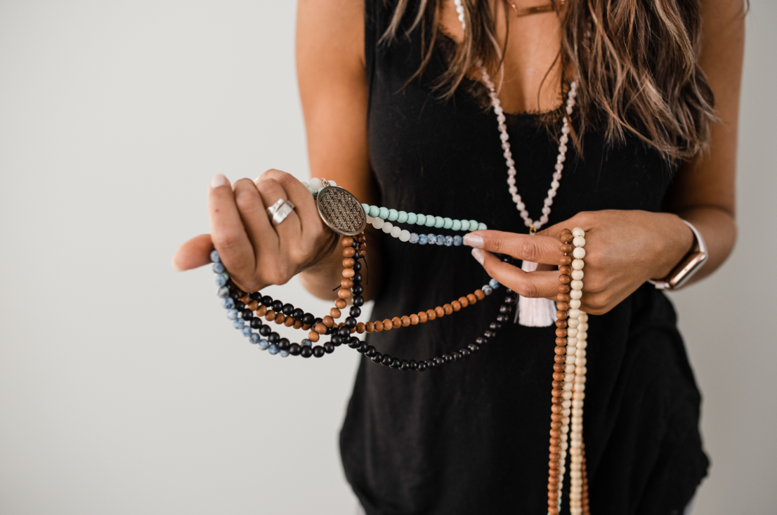 A woman holding a collection of beautiful handmade malas, often used during meditation or yoga.