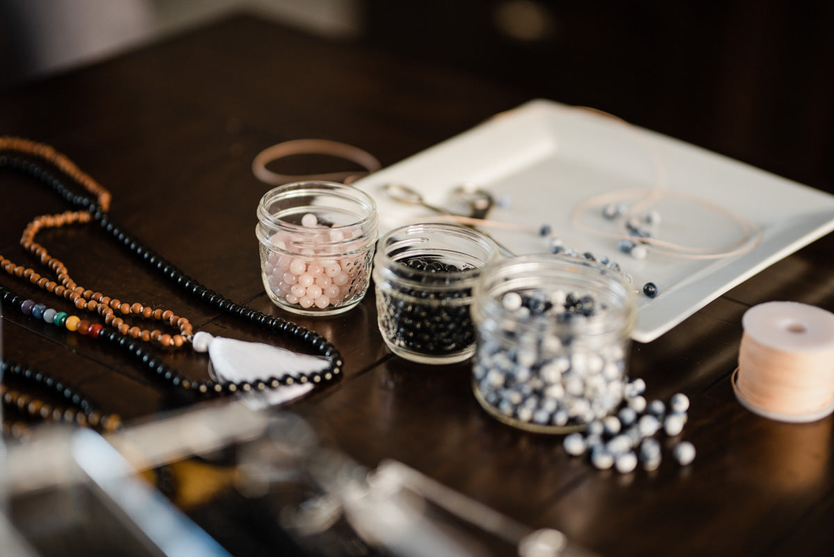 A collection of ethically-sourced mala beads and other jewelry-making tools sits on a table.