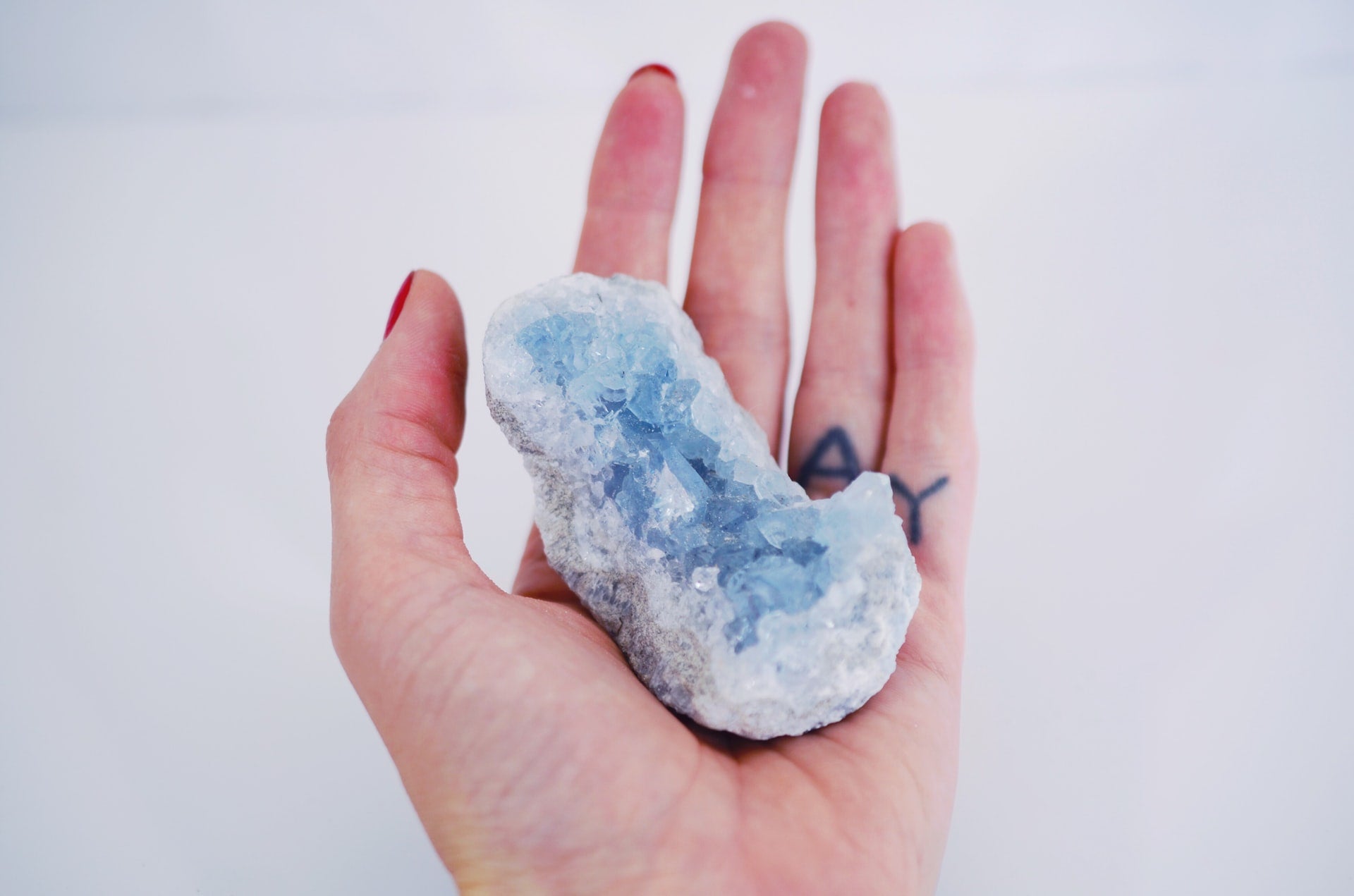 Hand holding a beautiful blue crystal, using it for its healing properties.