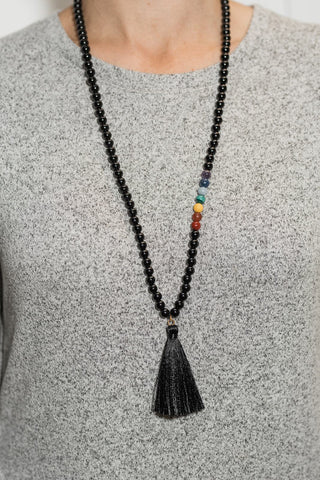 A handmade mala necklace using black obsidian, amethyst, sodalite, angelite, yellow jade, malachite, carnelian, and riverstone helps to balance the chakras.