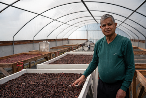 coffee farmer standing next to his coffee beans