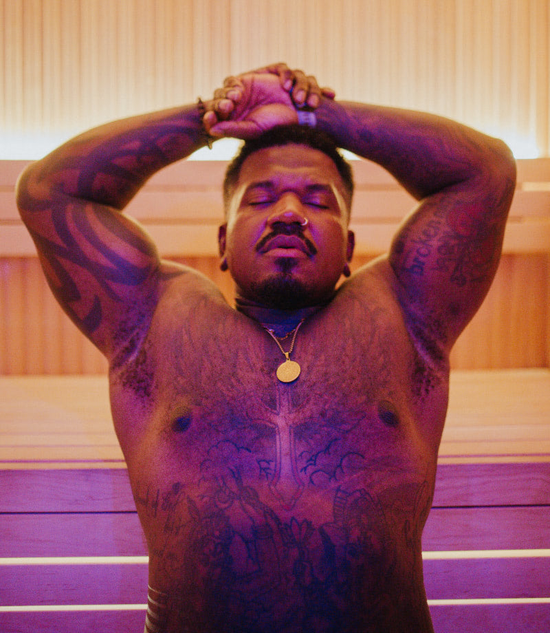 Closeup of a man stretching in the sauna with purple and yellow lighting