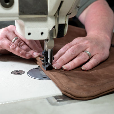 hands sewing a leather bag