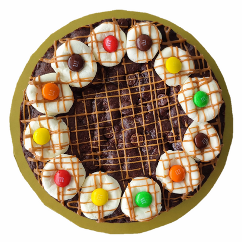Image is of a double chocolate cookie cake with M&m's and Biscoff drizzle