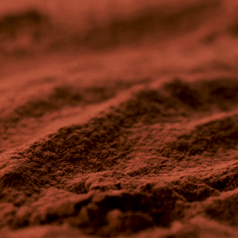 A gif showing cocoa powder being sprinkled into a pile of more cocoa powder