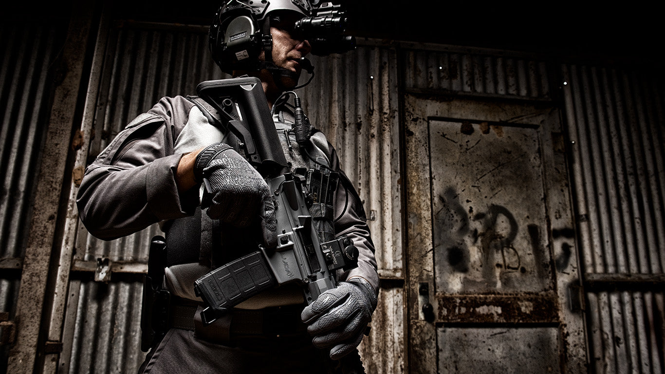 Armed professional showcasing Mechanix Wear The Original Wolf Grey Tactical Gloves during active duty.