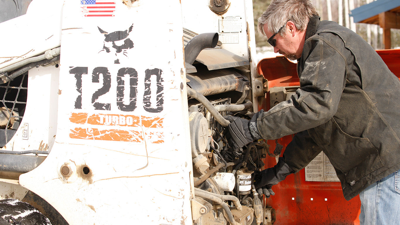 Mechanic wearing Mechanix Wear SpeedKnit™ Thermal S4DP05 gloves while working on a heavy-duty vehicle's engine.