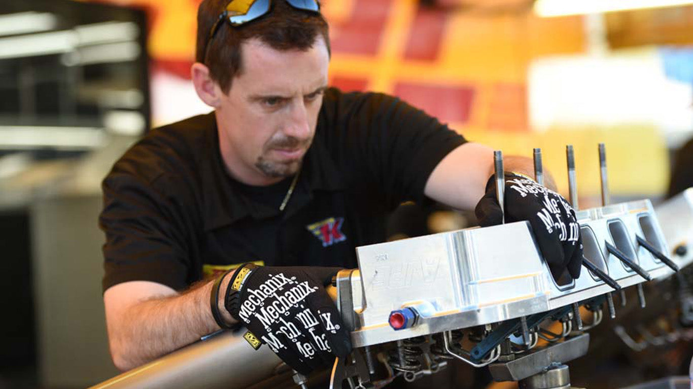 Focused technician wearing Mechanix Wear The Original Work Gloves while working on an engine.