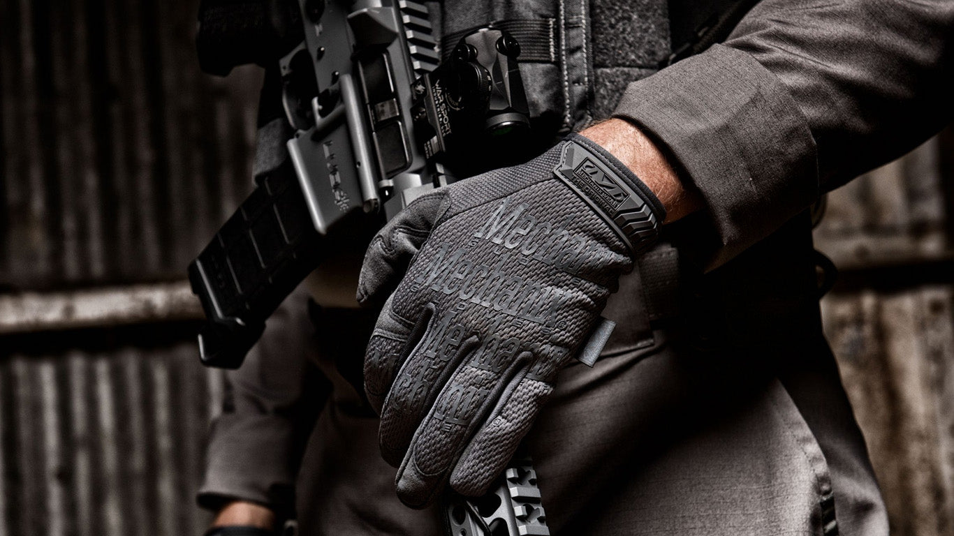 Armed professional showcasing Mechanix Wear The Original Wolf Grey Tactical Gloves during active duty.