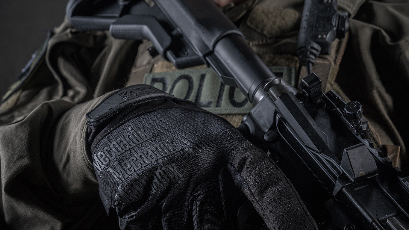 Close-up of an officer’s hand outfitted with Mechanix wear specialty vent covert tactical gloves, steadying a service weapon during duty.