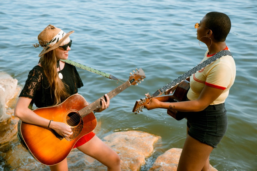 Two girls with handwoven Original Fuzz guitar straps standing by the lake in Nashville.
