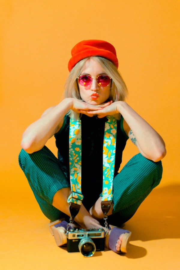 Girl posing with vintage camera strap for 60s mod photoshoot.