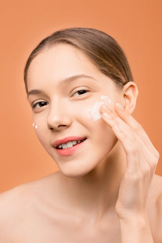Woman applying a moisturizer on her skin 