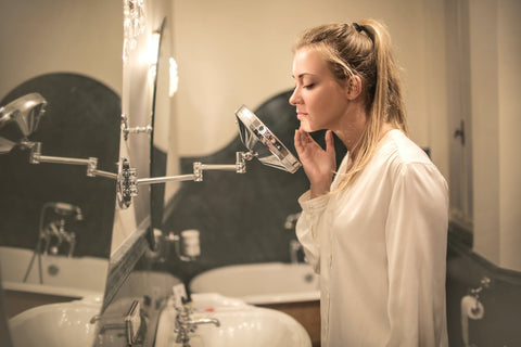 Woman looking at her skin in the mirror 