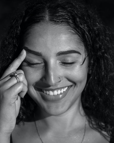 A smiling woman with her finger on her forehead 