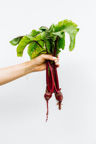 A hand holding 2 beetroots 